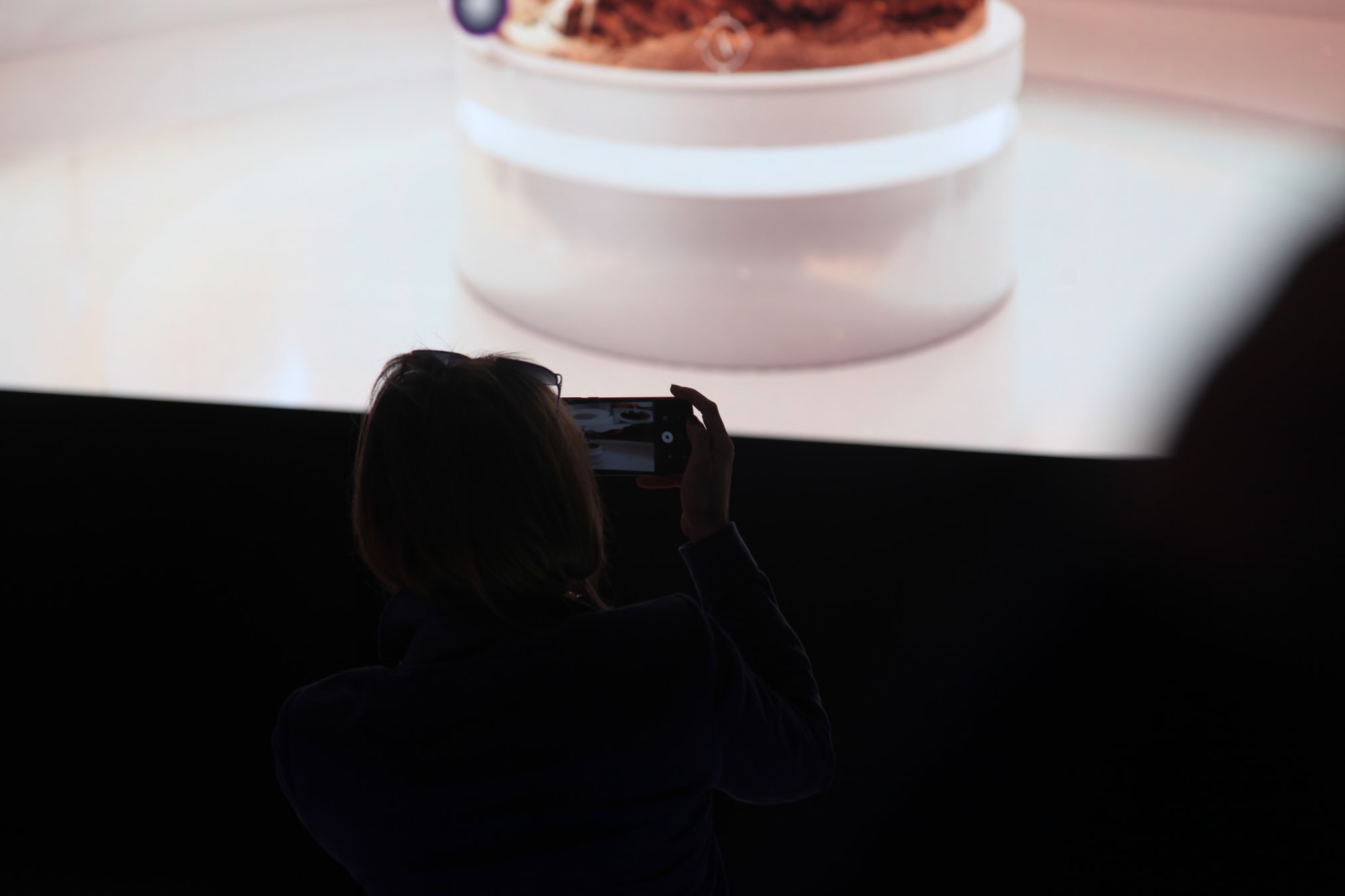 Visitor capturing the live broadcast on the stand's LED wall